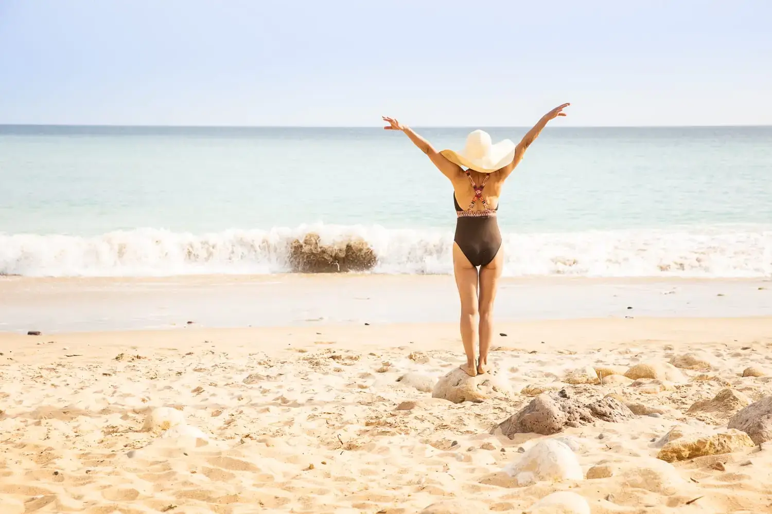 Woman in a swimsuit by the sea, arms wide open